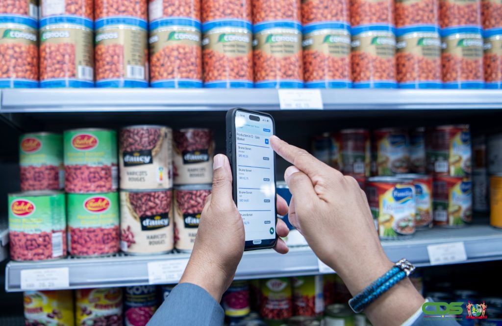 Een smartphone met de prijscontrole-app SRD Check voor een schap met bonen in een supermarkt.