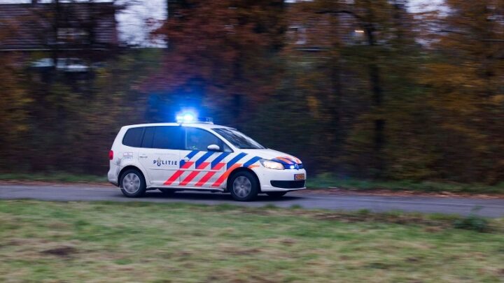 Een Nederlandse politieauto met blauwe zwaailichten, ter illustratie.